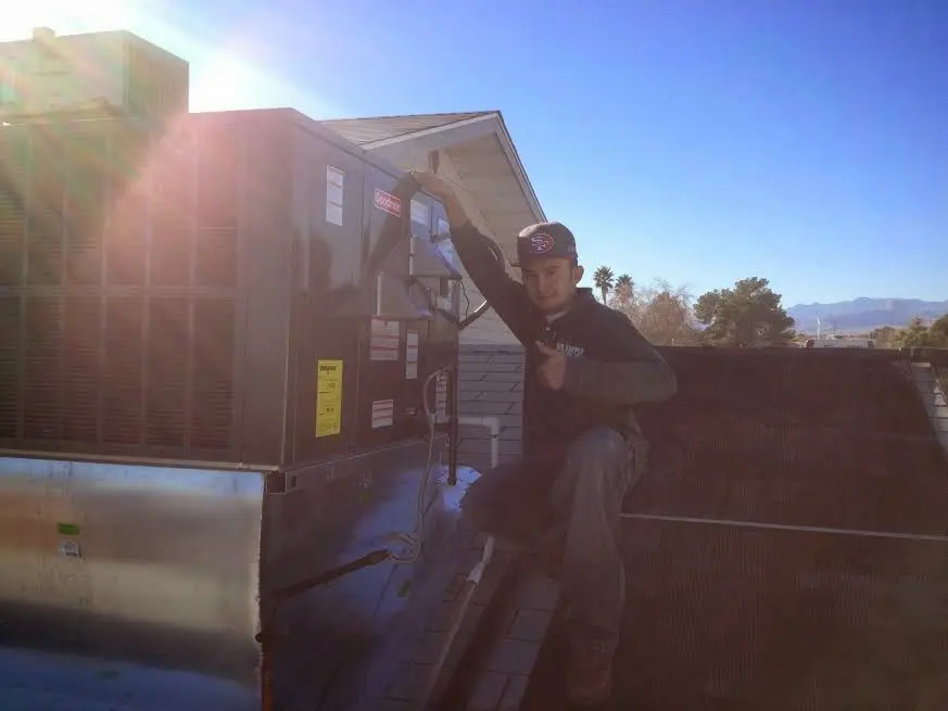 HVAC technician performing Air Duct Cleaning on a rooftop unit in Seymour
