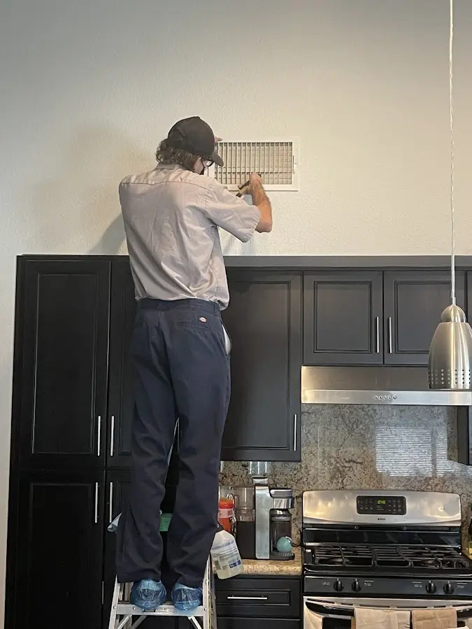 Technician inspecting an air vent during HVAC service in Seymour